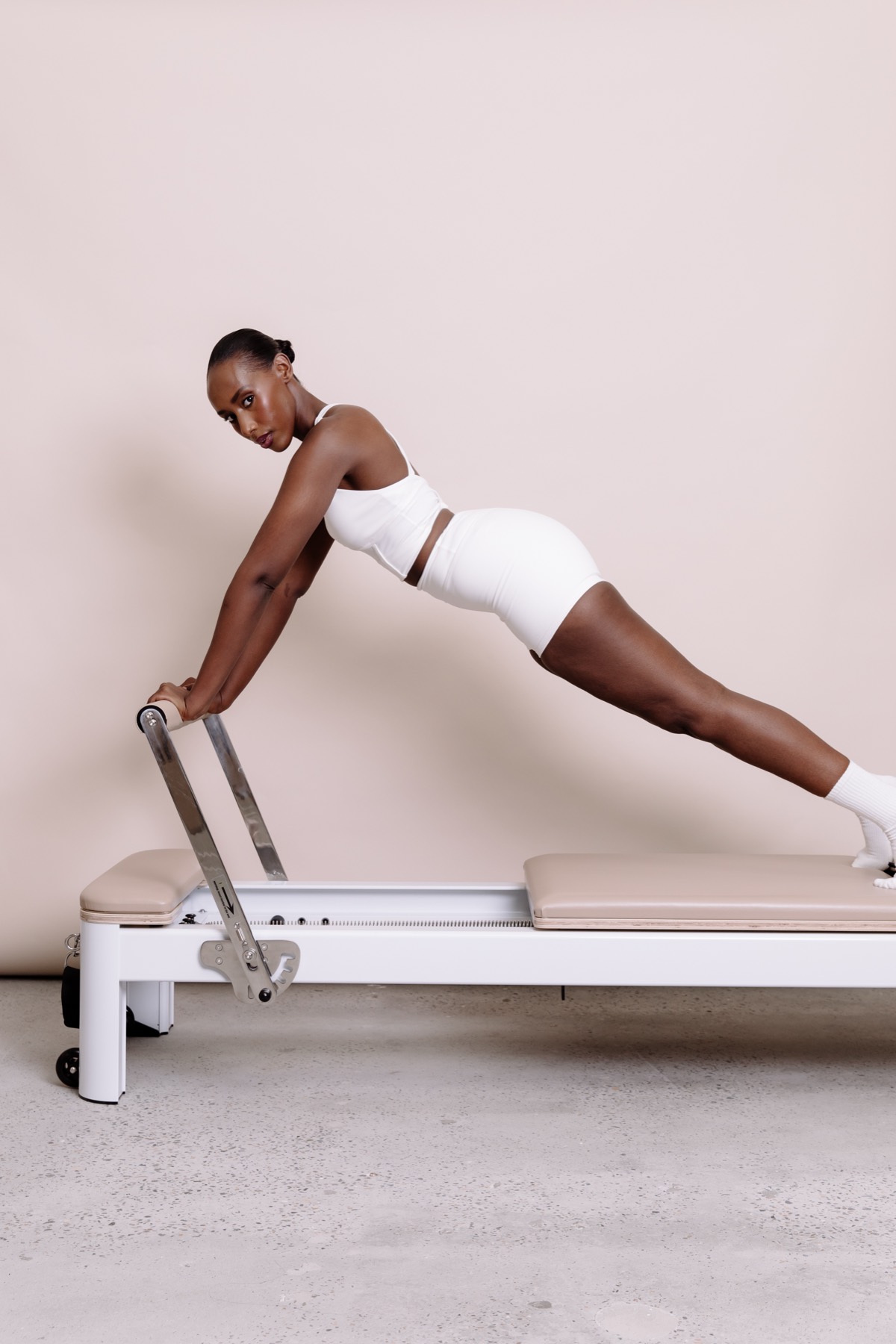 Woman in a plank position with hands on the reformer